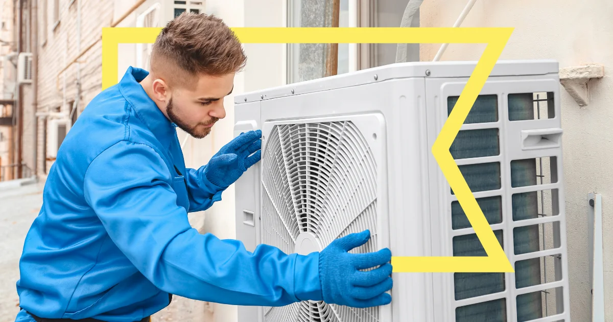 Technician in blue coveralls and blue gloves installs an air conditioner and is outlined by a yellow Coastal flag.