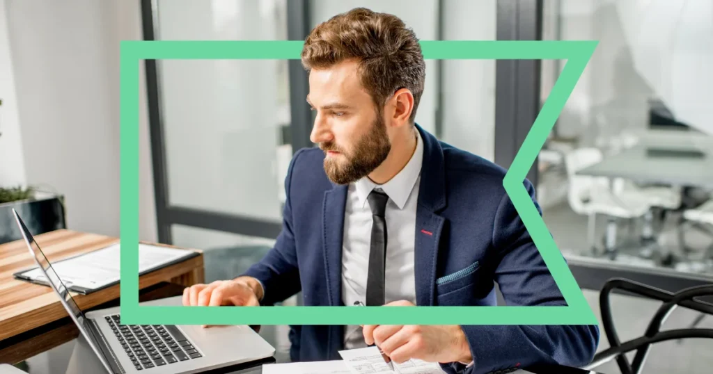 Business professional working at a laptop in a modern office setting.