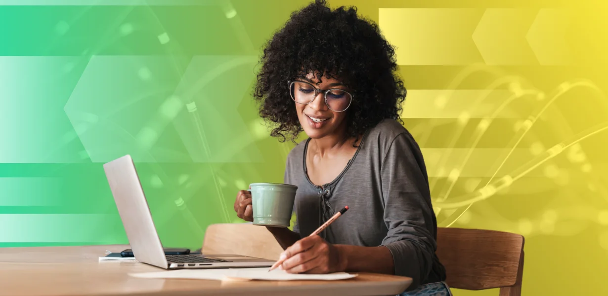 Woman holding coffee cup taking notes at a computer
